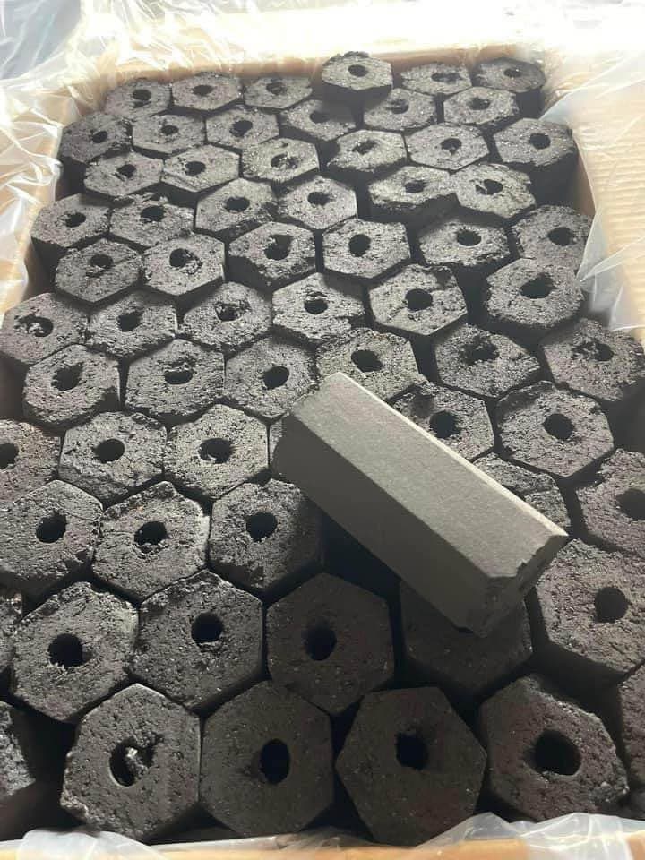 A one-kilogram inner box beside a master carton, with hexagonal coconut charcoal briquettes in front